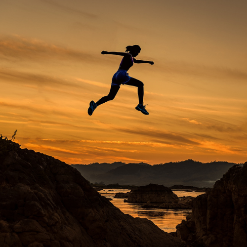 Woman leaping between two mountains.